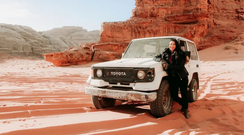 A 4x4 pickup parked on rippled red sand below Wadi Rum's cliffs