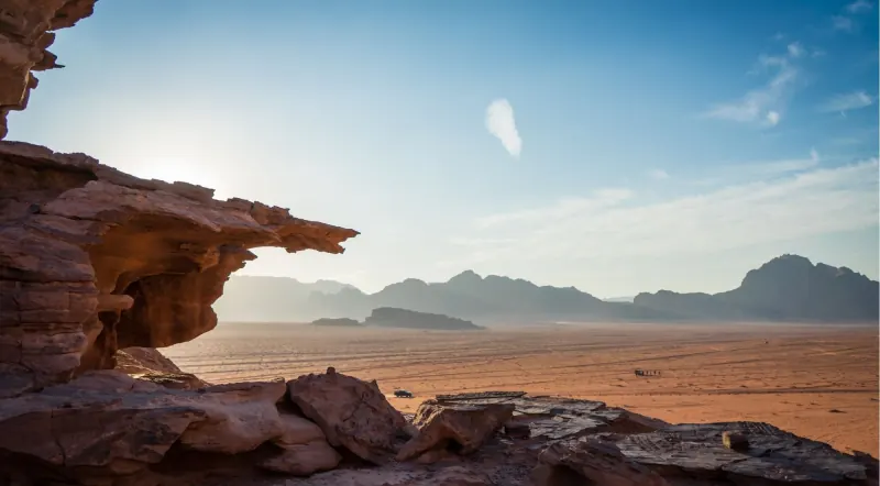 A wide view across the Wadi Rum desert plain from beneath a rock overhang