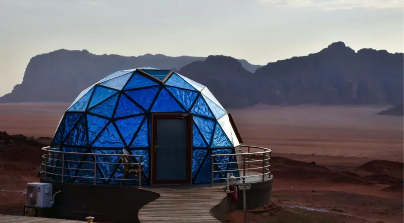 A single transparent Martian dome tent facing the open Wadi Rum desert