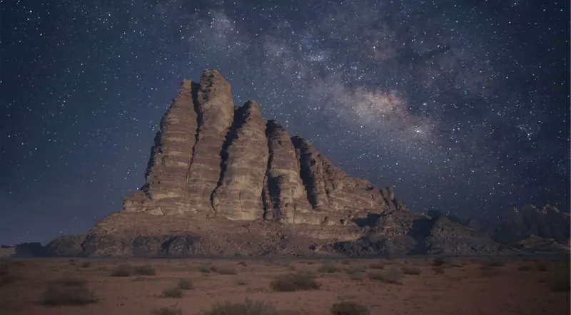 The Milky Way arching over a sandstone massif in Wadi Rum at night