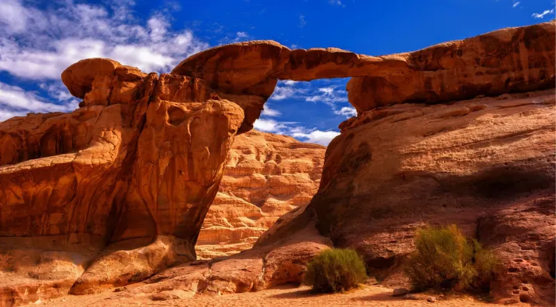 A natural sandstone rock bridge arching over the desert in Wadi Rum